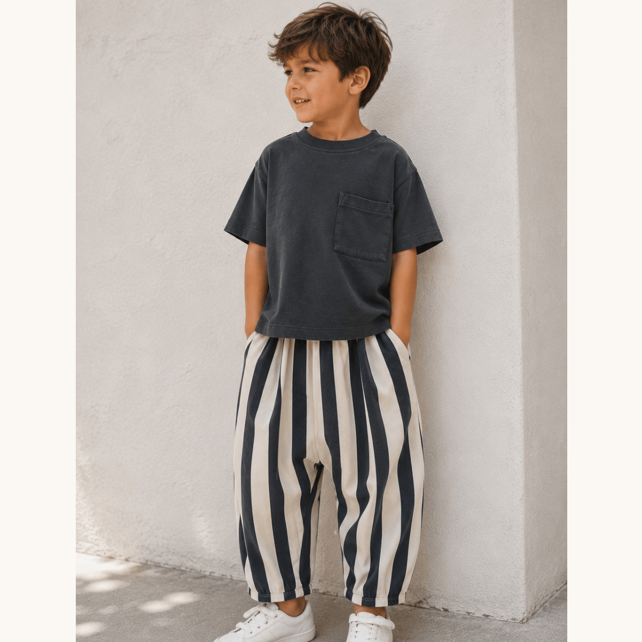 Boy in black and cream pants standing against the wall